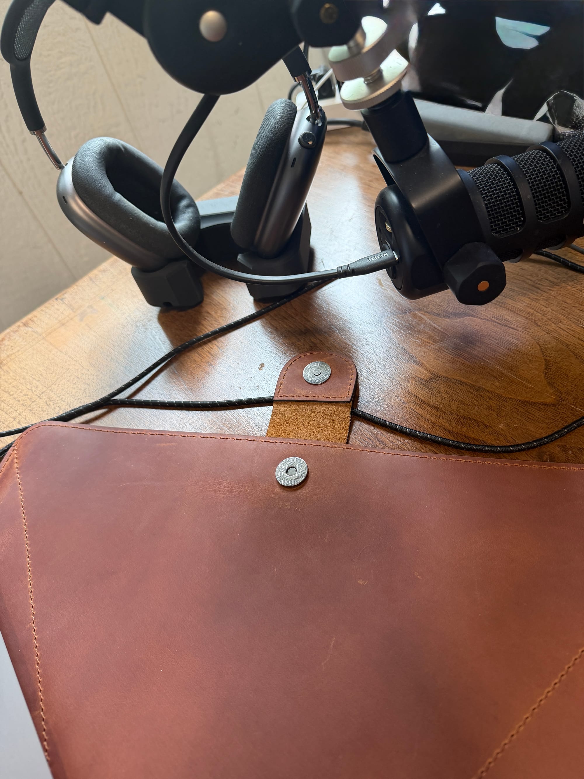 The sleeve on a wooden desk under a podcast microphone and headphones, the clasp button visible at center