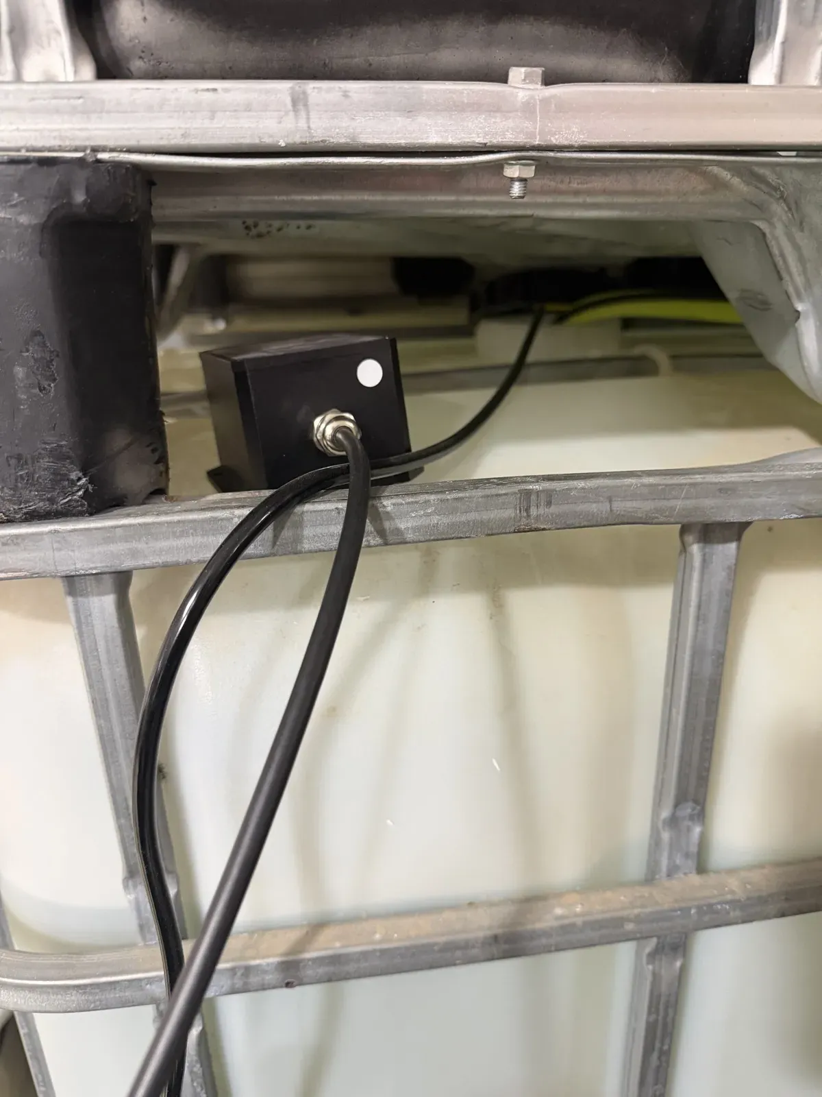 IBC tote cistern with a level-sensor enclosure mounted on its galvanized cage