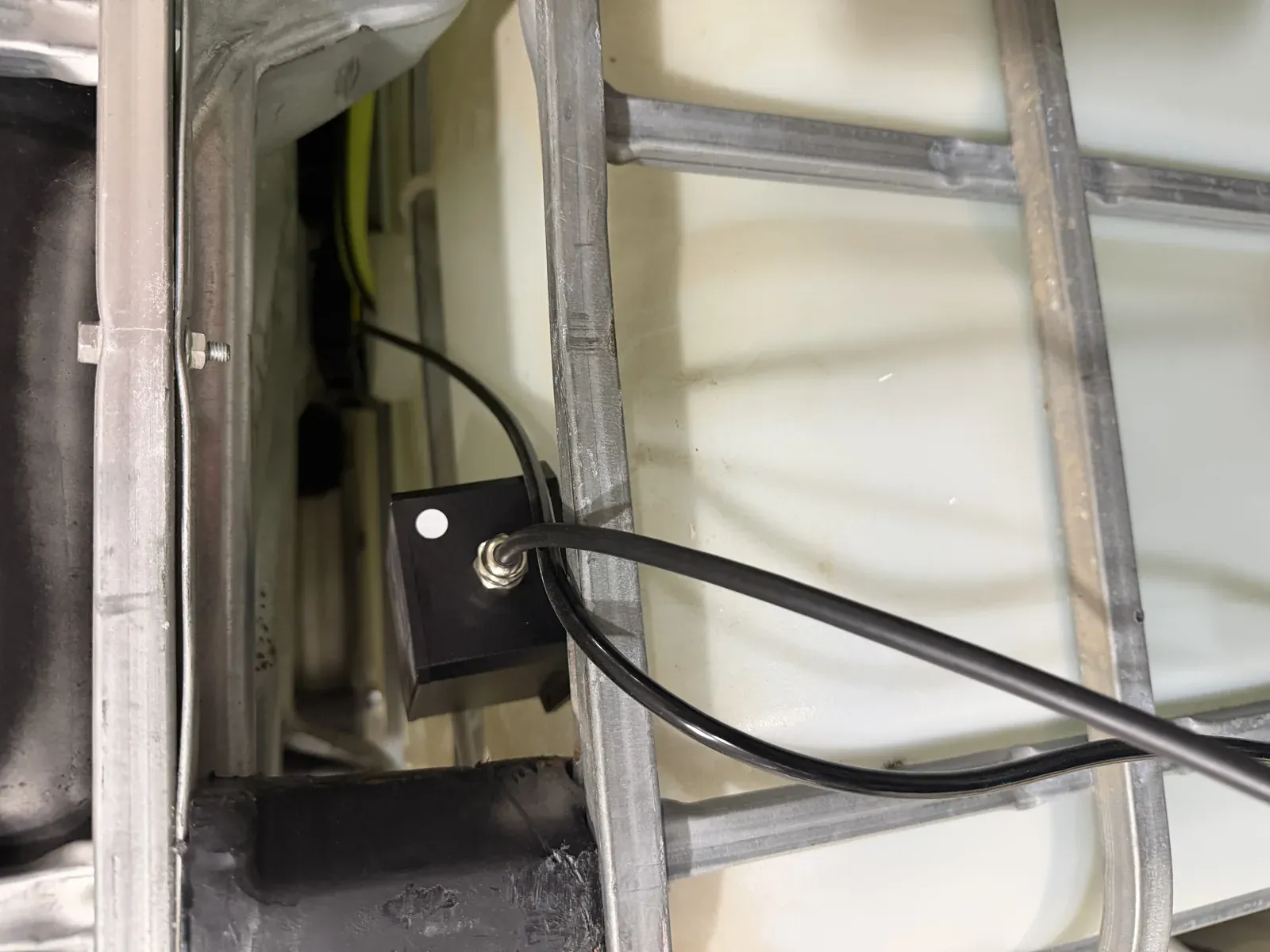 The Rejeee SL711 level sensor mounted on the galvanized cage of a shop IBC tote, probe cable into the tank