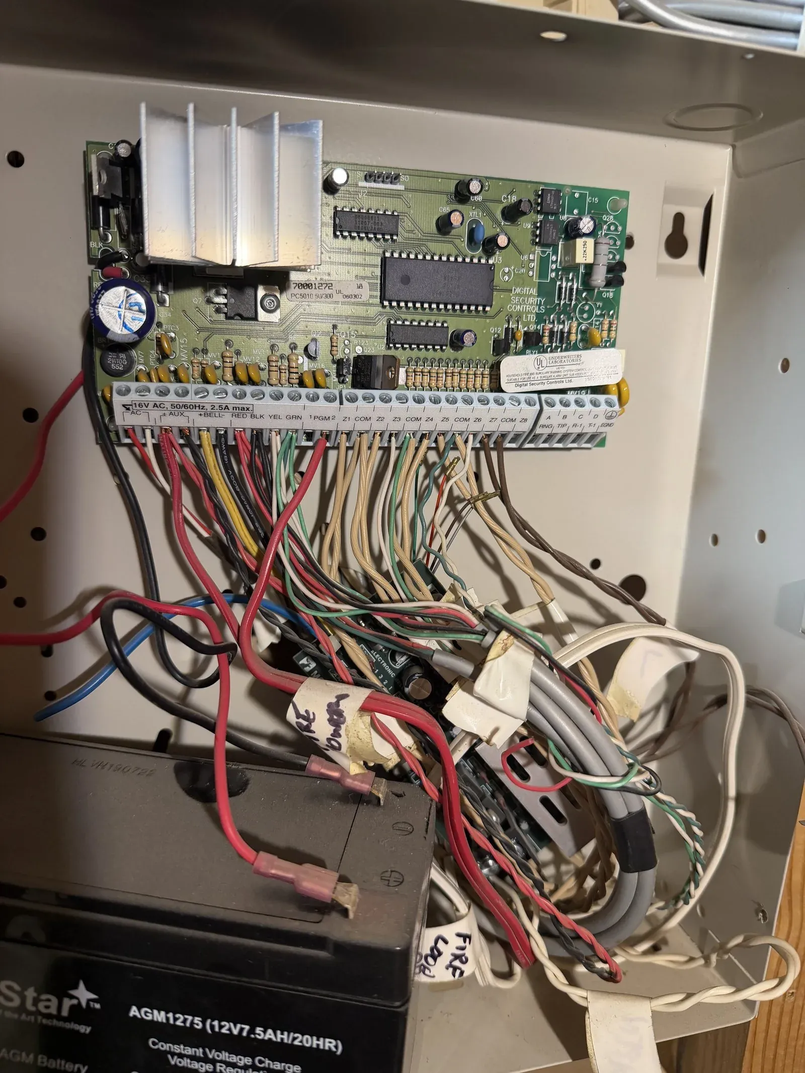 The DSC PowerSeries circuit board and its labeled screw-terminal strip inside the panel can
