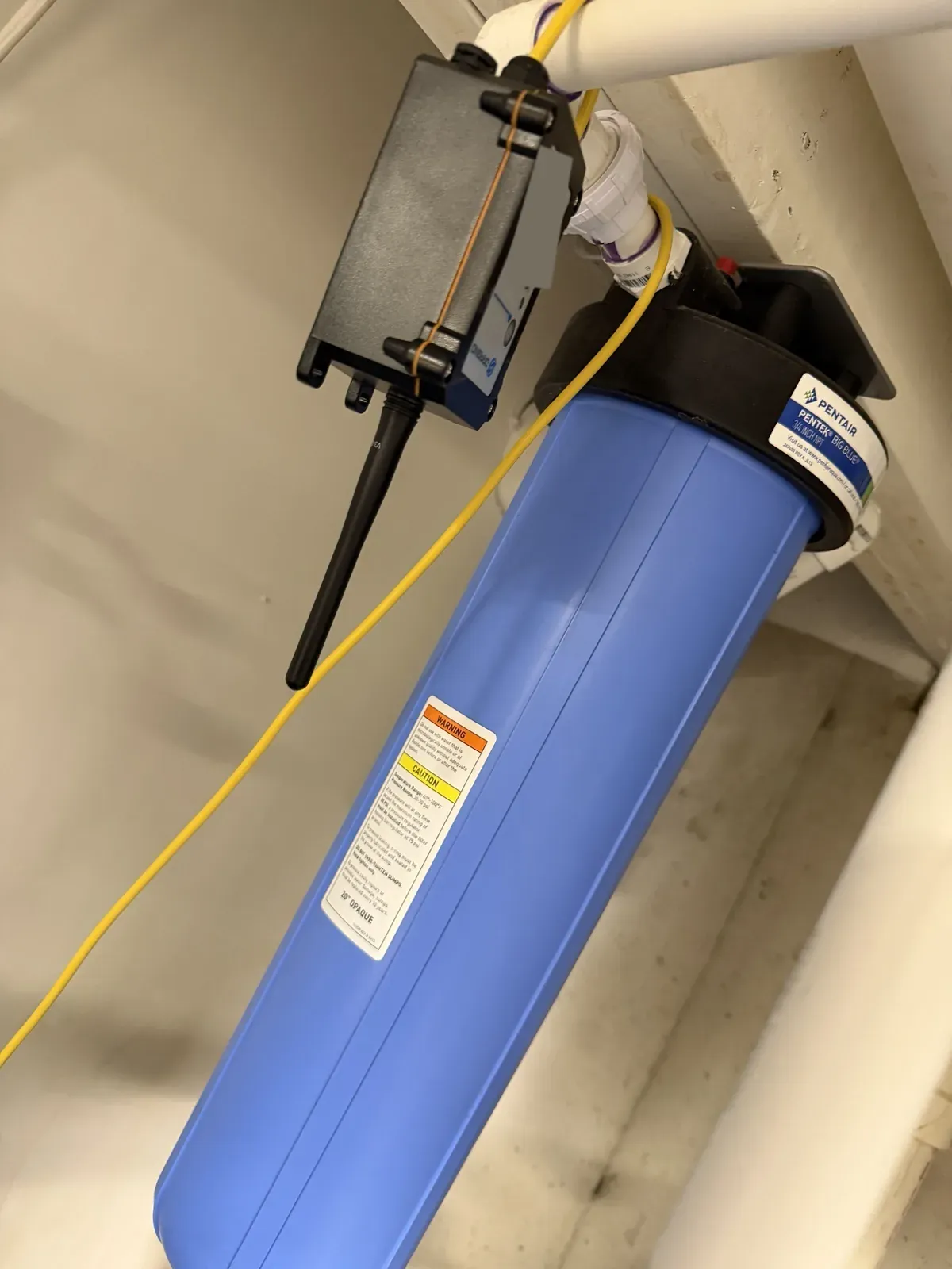 The Dragino sensor body strapped to a PVC line above the filter housing